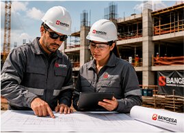 Dos ingenieros revisando planos frente a una construcción